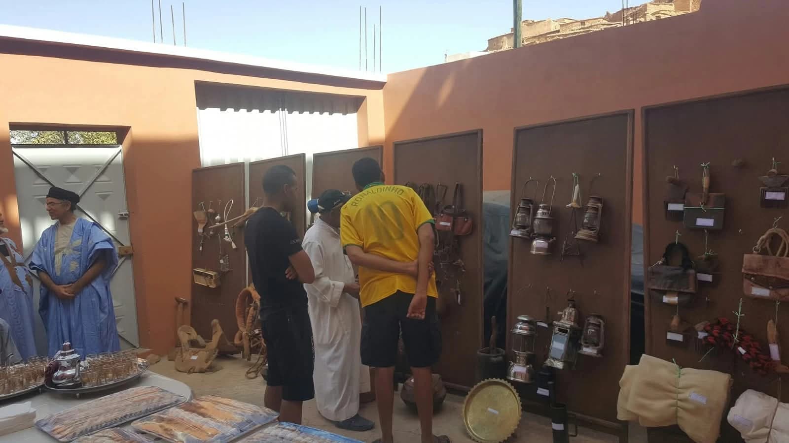 زوار أمام ألواح المعرض، وقد عُلّقت عليها مصابيح الكاز وأدوات من الجلد وأدوات قديمة.